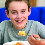 Boy eats Scottish salmon pasta with red label